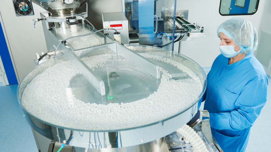 Quality control specialist inspecting pharmaceutical tablets in a production facility.
